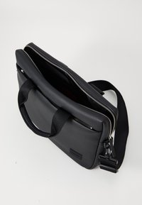 Black leather bag with textured surface, silver zipper, dual handles, and adjustable strap. Includes interior compartment and branding detail.