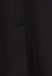Black fabric with a smooth texture featuring a side pocket. Simple design, no visible patterns or embellishments. Clean, understated look.