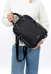 Black nylon backpack with dual handles, adjustable straps, and silver zippers. Features a sleek, minimalist design and textured accents.