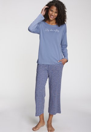 Light blue long-sleeve top with "Sleep solves everything" text, paired with patterned blue and pink striped loose pants.