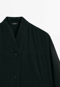 Black button-up jacket made of textured fabric, featuring a wide collar, a single button closure, and a relaxed fit.