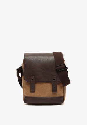 Bolso mensajero de cuero marrón y lona color arena con tapa, correa ajustable y acentos metálicos. Forma rectangular con materiales texturizados.