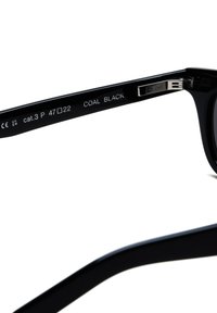 Musta aurinkolasit, joissa on kiiltävä kehys, kaiverruksia varressa ja suorakulmainen muoto. Mukana "COAL BLACK" -merkintä ja kategorianumero.