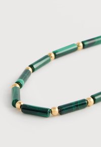 Κολιέ από χάντρες μαλαχίτη σε πράσινο χρώμα, με κυλινδρικά τμήματα και σφαιρικές λεπτομέρειες σε χρυσαφί απόχρωση, παρουσιάζοντας ομαλή, γυαλιστερή υφή σε όλο το μήκος.