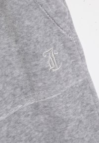Felpa grigia con un tessuto strutturato, decorata con una lettera "J" bianca ricamata sul fronte e dettagli cuciti visibili.