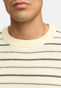 Lyscreme strikket sweater med vandrette sorte striber, udstyret med en ribbet rund hals og struktureret stof.