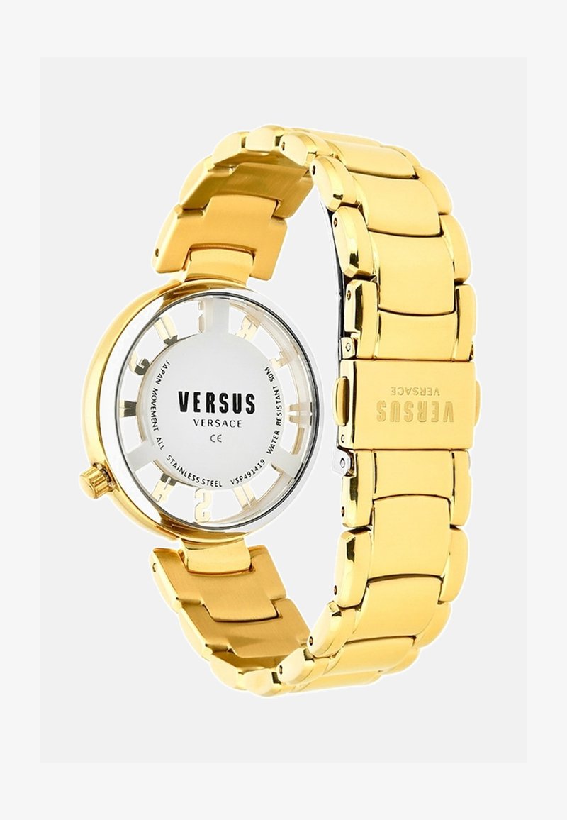 Aukso nerūdijančio plieno laikrodis su apvaliu korpusu, atviru ciferblatu, rodančiu VERSUS prekių ženklą, bei masyviu grandine. Atsparus vandeniui.