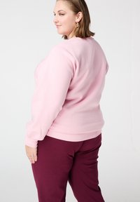 Lichtroze sweatshirt met lange mouwen, geribbelde manchetten en een ronde hals, gecombineerd met bordeauxrode broek, zachte stoftextuur, losse pasvorm.