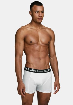 Weiße Baumwoll-Boxershorts mit einem schwarzen Bund, auf dem der Text "JACK & JONES" steht, präsentiert an einem männlichen Modell mit muskulösem Körperbau.