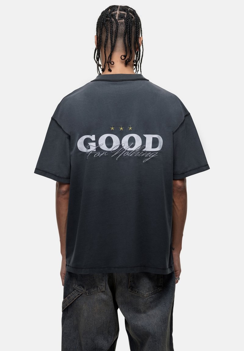 Czarna szara, oversize'owa koszulka z krótkim rękawem, na plecach z białym napisem "GOOD" i "for Nothing", z trzema gwiazdkami nad tekstem.