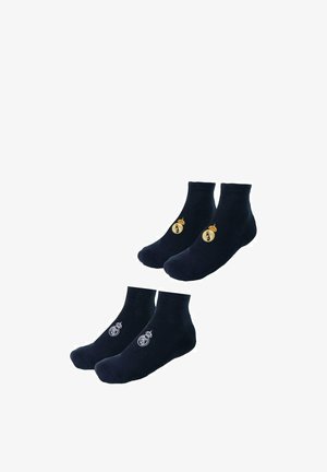 Twee paar zwarte enkelsokken met het embleem van voetbalclub Real Madrid, het ene paar met een gouden logo en het andere met een wit logo.
