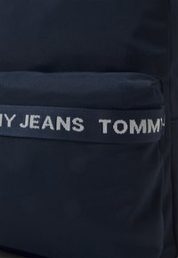 Granatowy plecak z tkaniny, z przednią kieszenią z wyhaftowanym logo "TOMMY JEANS" oraz lekko wyściełanym designem dla dodatkowego komfortu.
