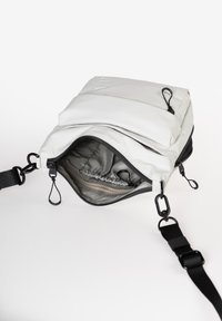 Borsa multifunzionale bianca con apertura con cerniera, esterno testurizzato, tracolla regolabile e tasche interne. Presenta dettagli in metallo di colore nero.