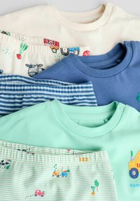 Vier gevouwen babyoutfits in pastel crème, blauw en groen met kleine voertuigen en dierenprints, en drukknoopjes op de schouders.