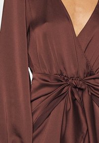 Brun satin wrap-klänning med långa ärmar, djup V-ringning och knuten midja med draperade tygdetaljer.