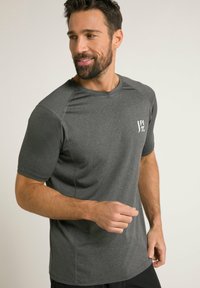 Graues sportliches T-Shirt mit kurzen Ärmeln, rundem Halsausschnitt und kleinem weißen Logo auf der Brust. Glatte Textur und taillierte Passform.