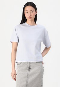 Licht lila t-shirt met korte mouwen, gemaakt van zachte katoen, met een ronde halslijn en een relaxte pasvorm, gecombineerd met een denim rok.