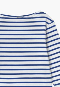 Biała koszula z długim rękawem z niebieskimi poziomymi paskami. Posiada szeroki dekolt i miękką fakturę tkaniny. Z metką widoczną od wewnątrz.