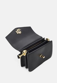 Black leather handbag with a gold logo, zippered compartment, and chain strap. Features clean lines and a smooth texture.