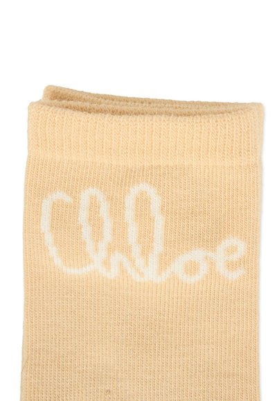 Calzino color pesca realizzato in tessuto lavorato a maglia con una finitura testurizzata. Presenta il logo bianco in corsivo "Chloe" vicino al polsino.