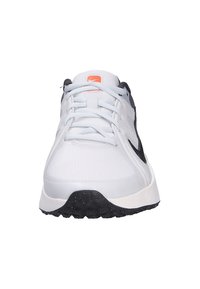 Zapatilla de running de Nike con parte superior blanca transpirable y detalles en negro, suela texturizada y un logo y ojales en rosa contrastante.