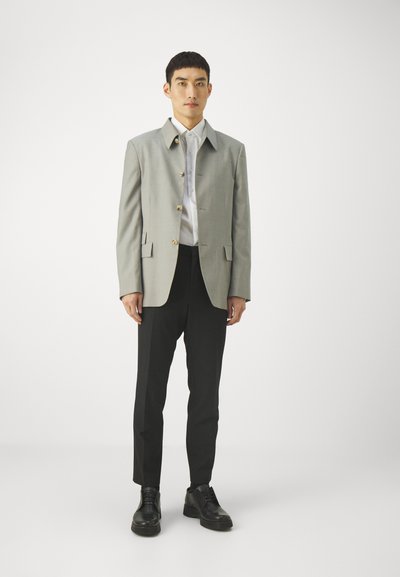 Light gray blazer with gold buttons, paired with a white shirt and black tailored trousers. Black shoes complete the outfit.
