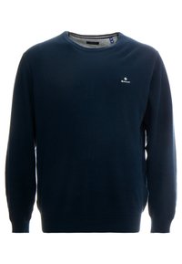 Marineblauwe gebreide trui met een ronde hals, geribbelde manchetten en zoom. Voorzien van een klein wit logo op de borst. Geheel met een gestructureerd patroon.