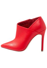 Botín de tacón alto de cuero rojo con punta puntiaguda, diseño elegante y detalles de recortes angulados en la parte frontal y los laterales.