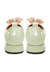 Mintgroene patenten leren schoenen met een vierkante neus, voorzien van een stevige zwarte zool en decoratieve accenten op de hakken.