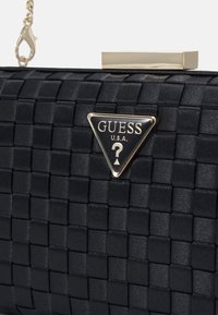 Clutch bag nera intrecciata in satin con una chiusura in metallo dorato e una placca logo triangolare che presenta il nome del marchio e un punto interrogativo.