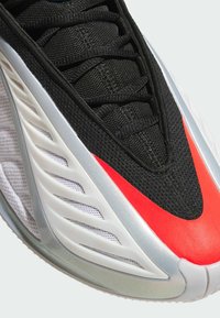 Μαύρο αθλητικό παπούτσι με υφασμένο επάνω μέρος από πλέγμα, κόκκινες λεπτομέρειες και λευκή υφασμένη ενδιάμεση σόλα με ανοίγματα για αερισμό και ευκαμψία.