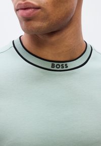 Ανοιχτό πράσινο κοντομάνικο μπλουζάκι με ριγωτό μαύρο λαιμόκοψη και κεντημένο λογότυπο "BOSS", με μαλακή βαμβακερή υφή κα ι casual σχεδιασμό.