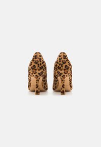 Tacones altos con estampado de leopardo, material texturizado de piel, forma cónica y tacón de aguja de altura media. Presentan un pequeño recorte en la parte trasera.