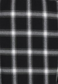 Czarnobiała tkanina w kratę z wzorem siatki; zawiera cienkie białe linie i kwadratowe akcenty. Teksturowane wykończenie.