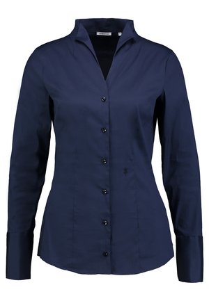 Chemise bleu marine à manches longues avec un col, cinq boutons et un détail logo floral subtil près de l'ourlet. Texture de tissu lisse.