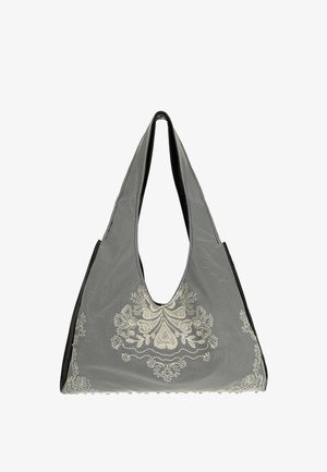 Harmaa kangasolkaiminen laukku leveillä olkahihnoilla, jossa valkoinen kukkakirjailu keskellä edessä ja jatkuu sivuille.