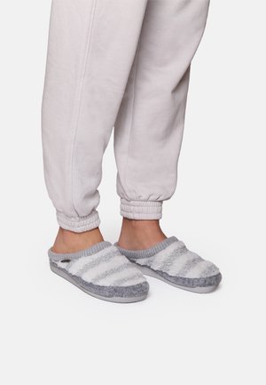Gray and white striped slippers with a soft, fuzzy texture. Open back and rounded toe design. Worn with gray cuffed sweatpants.