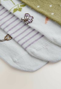 Patru perechi de șosete în modele diferite: o pereche verde texturată, o pereche albă cu dungi mov și fluture, și alta albă cu accente florale.