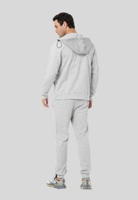 Hellgrauer Hoodie und passende Jogginghose, mit einer Kordelzugkapuze, gerippten Bündchen und einer strukturierten Oberfläche, kombiniert mit mehrfarbigen Sneakern.