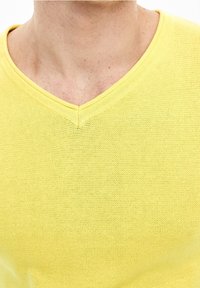 T-shirt giallo a scollo a V, tessuto lavorato a maglia, maniche corte, tessuto leggero, caratterizzato da un motivo sottile e un collo rinforzato.