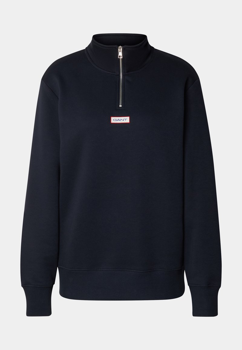 Navy pullover sweatshirt with a raised collar, half-zip closure, and a small red and white logo patch on the chest. Soft, cotton blend material.
