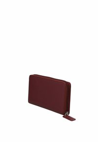 Portefeuille zippé rouge fabriqué en matériau synthétique texturé, présentant une forme rectangulaire slim et une petite étiquette sur la tirette du zip.