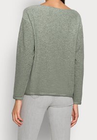 Vihreä tekstuurinen neulepaita, jossa on väljä istuvuus, pyöreä kaula-aukko ja pitkät hihat. Suunniteltu hienovaraisilla paksuusvaihteluilla ja suoralla helmalla.