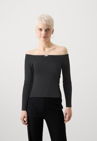 Juoda off-the-shoulder ilgarankovė palaidinė su baltomis taškelėmis, turinti mažą baltą kaspiną apykaklėje. Lygi audinio tekstūra.