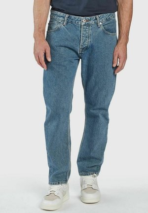 Blaue Jeans aus Denim mit klassischem geradem Schnitt, ausgestattet mit einem Fünf-Taschen-Design, kontrastierendem Nähen und einem Reißverschluss. Tragen mit weißen Sneakern.