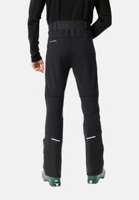 Pantalones de esquí negros con una textura suave, rodillas reforzadas y una cintura alta. Presenta acentos reflectantes y dobladillos ajustados.