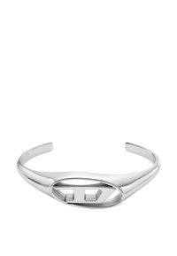 Pulsera de puño de plata con superficie lisa, forma ovalada alargada y diseño geométrico en corte que presenta un acento de doble triángulo.