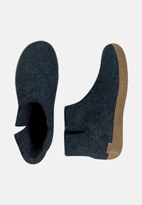 Mörkgrå filtankelskor med brun lädersula. Har en mjuk textur, minimalistisk design och sidöppningar för enkel påtagning.