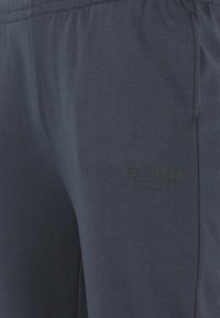 Mörkblå mjukisbyxor i en mjuk bomullsblandning med elastisk midja och en diskret logotryck på nedre vänster ben.