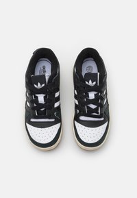 Svarta och vita sportskor med ovandel i läder, perforerat tåkasse, vadderad krage och tre vita ränder på sidan. Gummisula.